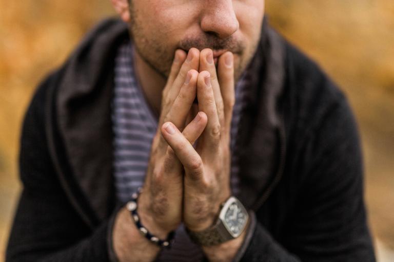 Man hold palms together on his mouth.